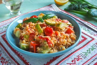 Bir plaka üzerinde yeşil mutfak masası sebzeli bulgur.