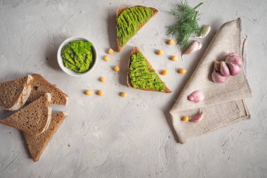 Kepekli ekmek Guakamole, nohut ve sarımsak ile gri beton zemin üzerinde dilimlenmiş.