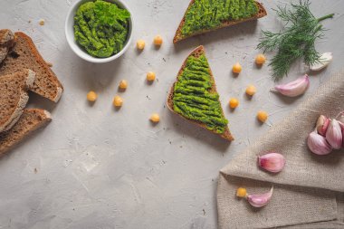 Kepekli ekmek Guakamole, nohut ve sarımsak ile gri beton zemin üzerinde dilimlenmiş.