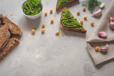 Kepekli ekmek Guakamole, nohut ve sarımsak ile gri beton zemin üzerinde dilimlenmiş.
