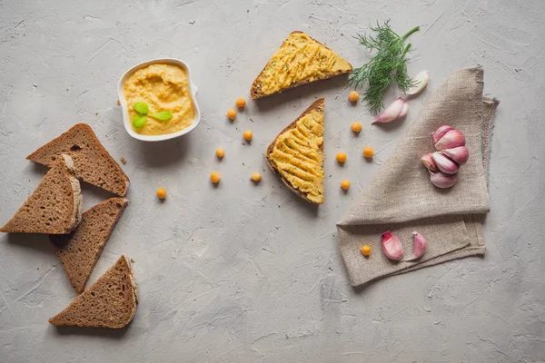 Kepekli ekmek Humus, nohut ve sarımsak ile gri beton zemin üzerinde dilimlenmiş. 