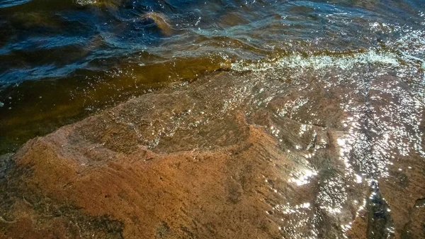 Graniet strand met golven en donker water. Noordelijke abstracte natuurlijke achtergrond. — Stockfoto