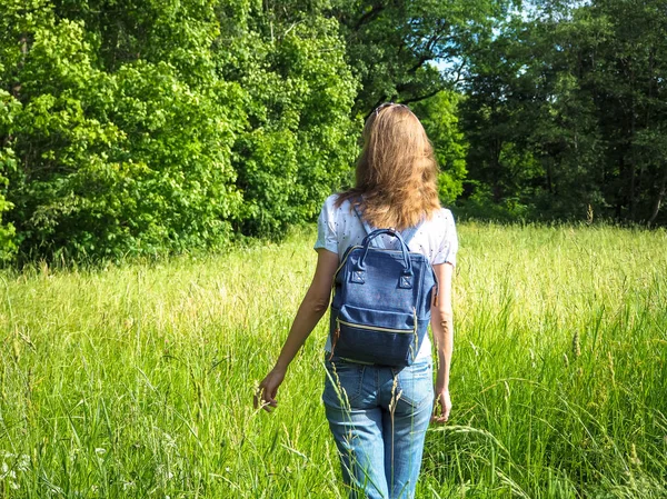 Bir sırt çantası ile ince bir kadın uzun boylu çimenlerin üzerinde seyahat.