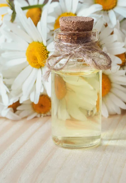 Botella de aceite de manzanilla con flores sobre fondo de madera . —  Fotos de Stock