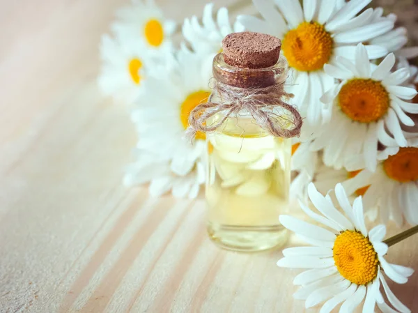 Heřmánkový olej láhev s květinami na dřevěné pozadí. — Stock fotografie