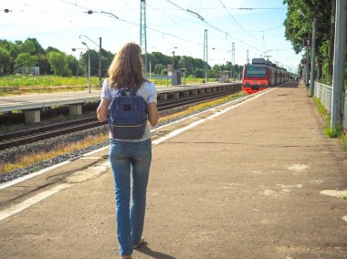 Küçük bir Avrupa şehrinde demiryolu platformunda sırt çantası ile Lady gezgin.