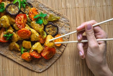 El tutma chopsticks bir parça tavuk. Körili tavuk parçaları ile pişmiş sebze ızgara.