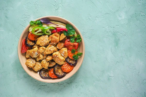 Bir plaka üzerinde ızgara sebzeli fırında et parçaları.