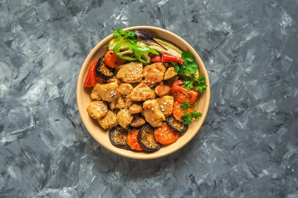 Bir plaka üzerinde ızgara sebzeli fırında et parçaları.