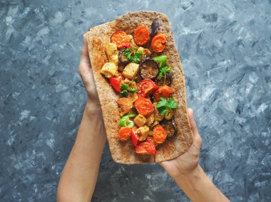 Tortilla onun elinde ızgara et ve sebze ile.