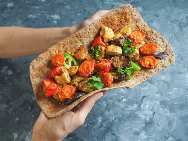 Tortilla onun elinde ızgara et ve sebze ile.