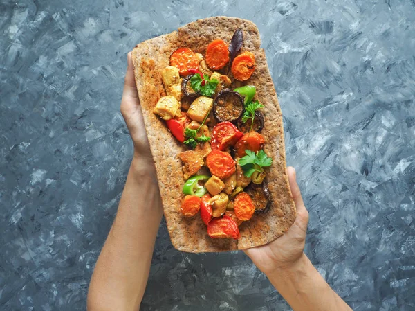 Tortilla onun elinde ızgara et ve sebze ile.