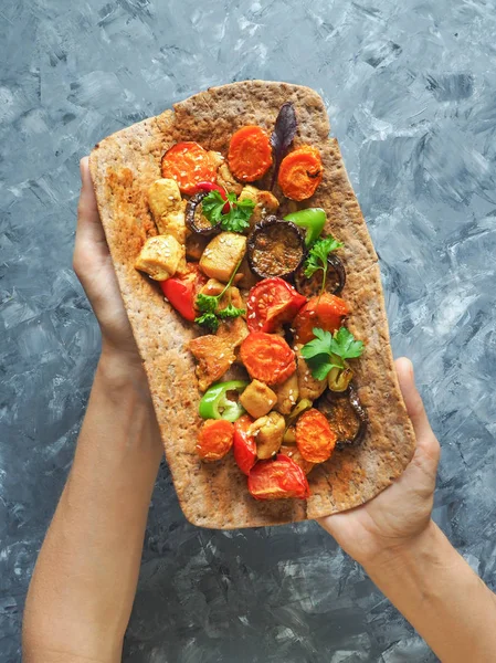 Tortilla onun elinde ızgara et ve sebze ile.