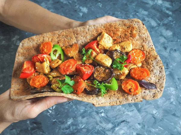 Tortilla onun elinde ızgara et ve sebze ile.