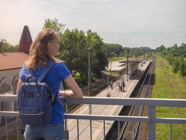 Nostalgia for travel. Lady with a backpack behind her on the train tracks in a small European city. — Stock Photo, Image