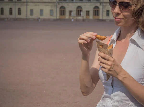 Uma menina segurando um pacote de batatas fritas na mão na rua. Pequeno pacote de batatas fritas, lanche rápido — Fotografia de Stock