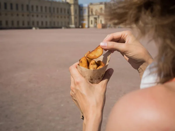 여자는 거리에 손에 튀김의 팩을 들고. 감자 튀김, 빠른 스낵의 작은 팩 — 스톡 사진