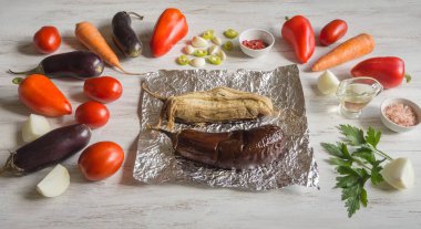 Patlıcan folyoyu pişmiş ve sebzeler üzerinde ahşap bir masa koyulur. Sebze ışık ahşap arka plan üzerinde.