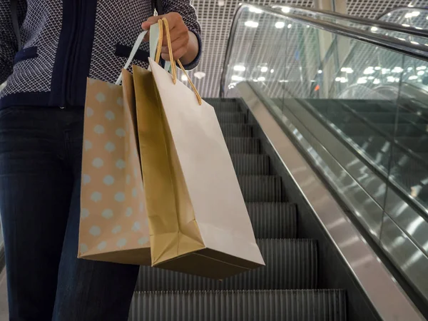Kadın yürüyen merdiven üzerinde paketleri ile.