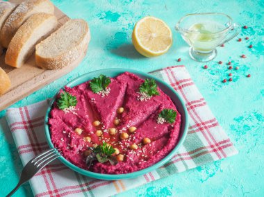 Mavi bir masaya bir tabak içinde geleneksel kırmızı humus.