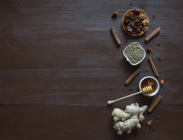 Ingrediënten op de bruine tabel voor het bakken met honing, gember, kaneel, kruidnagel, gedroogd fruit en hennep zaden. — Stockfoto