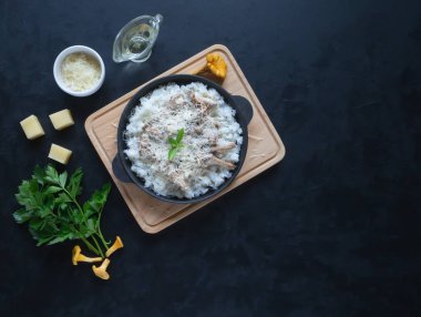 Risotto chanterelles dökme demir tava siyah bir masada.