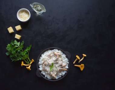 Risotto chanterelles dökme demir tava siyah bir masada.
