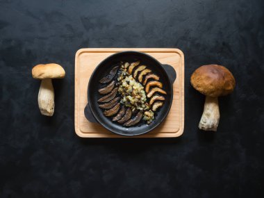 Penny topuz yemek. Fried cèpes bir demir siyah masaya pan. Üstten görünüm. 