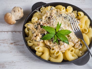 Ahşap masa üzerinde bir demir tavada cèpes ile makarna fırıncı.