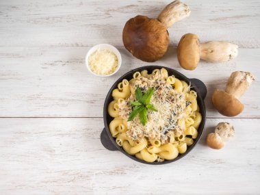 Makarna ile dökme demir kuruş çörek tava üzerinde beyaz bir ahşap masa.