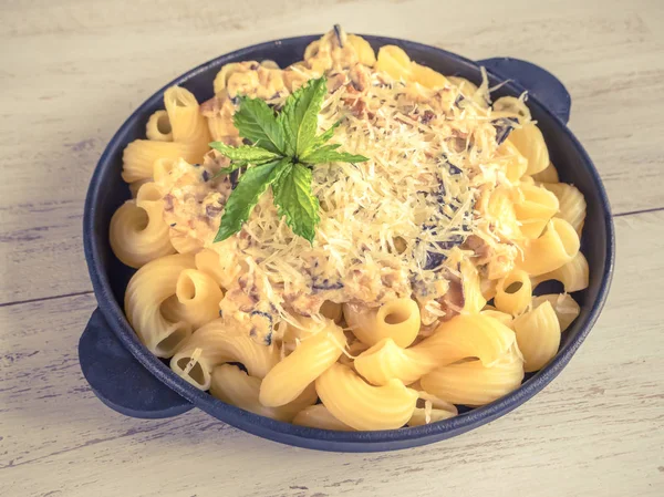 Makarna ile dökme demir kuruş çörek tava üzerinde beyaz bir ahşap masa.