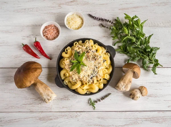 Makarna ile dökme demir kuruş çörek tava üzerinde beyaz bir ahşap masa.