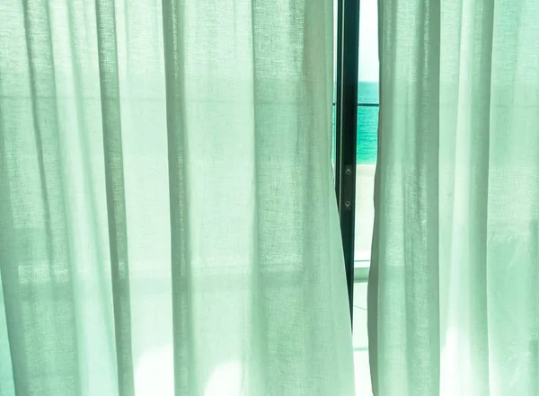 Fabric curtains on the window. Closed curtains window to the beach.