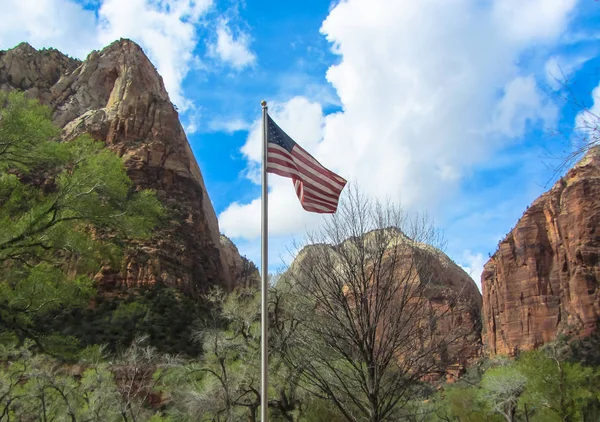 American flag on a mountain and cloudy sky background.