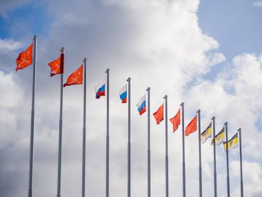 Flags on the flagpoles on the clouds background. clipart