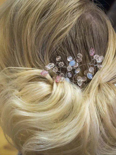 Hair stylist makes the bride a wedding hairstyle with hair detail accessory, closeup rear view. — Stock Photo, Image