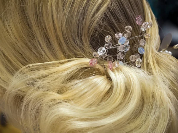 Hair stylist makes the bride a wedding hairstyle with hair detail accessory, closeup rear view. — Stock Photo, Image