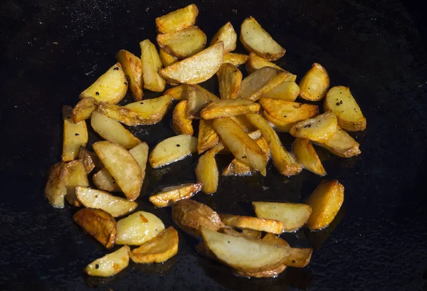 French fries frying in hot oil in a large pan.