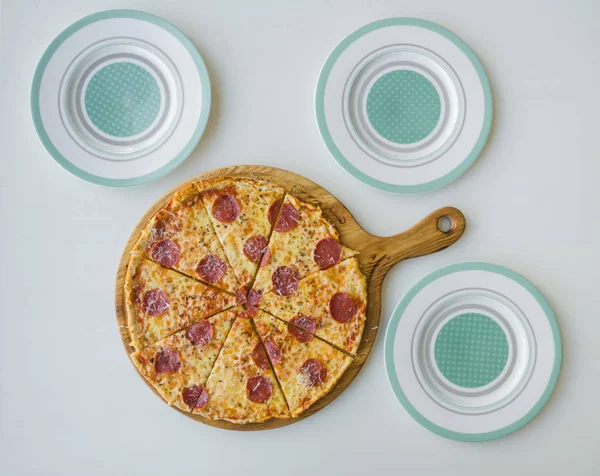 Pizza de pepperoni e três pratos vazios. Jantar familiar . — Fotografia de Stock