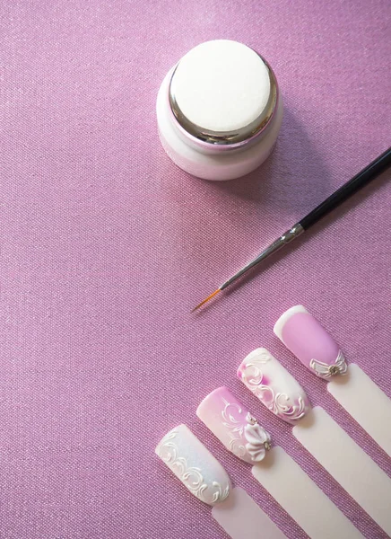 Nail design. Färg, penslar och typer på rosa bakgrund. — Stockfoto