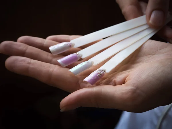 Paleta de muestras de diseño de uñas en manos de una manicura . — Foto de Stock
