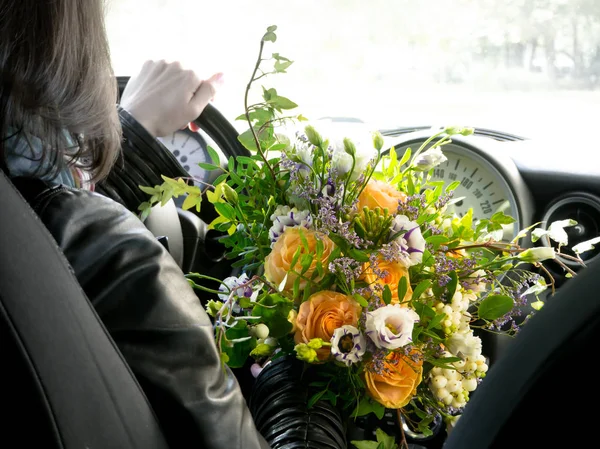 The driver behind the wheel with a bouquet of flowers.