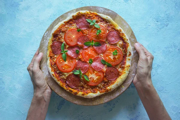 Pizza caseira com tomate e salsicha na mão . — Fotografia de Stock