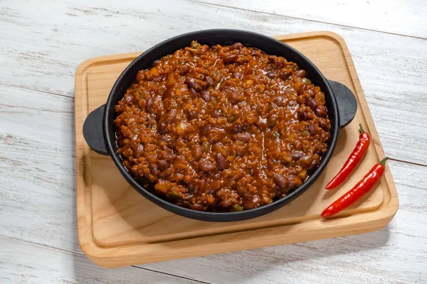 Mexican chili. Chili con carne in frying pan on white wooden background. — Stock Photo, Image