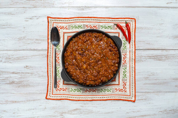 Мексиканское чили. Chili con carne в сковороде на белом деревянном фоне
. 