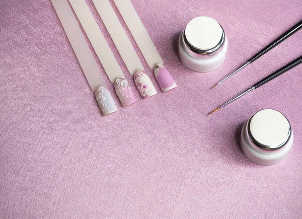 Consejos y pintura para dibujar en las uñas sobre un fondo rosa. Concepto de manicura creativa . — Foto de Stock