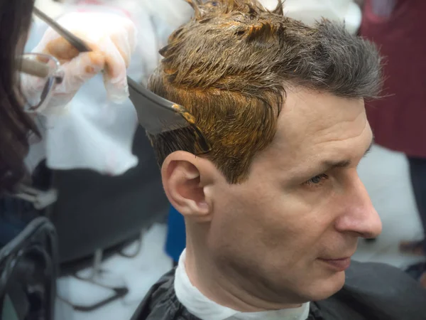 process of hair coloring on a man in beauty salon
