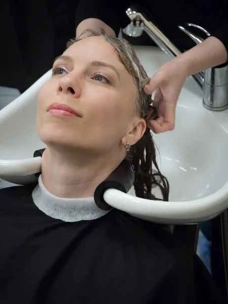 Una mujer se lava el pelo después de un corte de pelo . — Foto de Stock