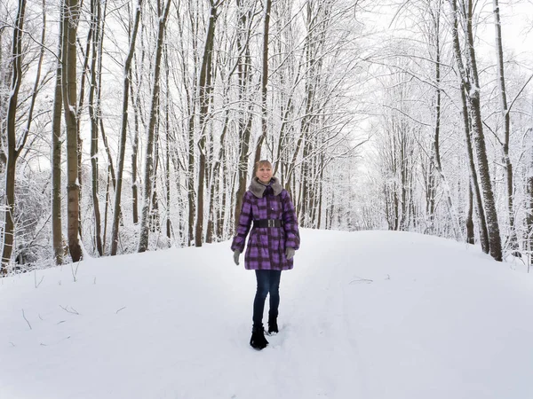 A slender young woman rejoices in a snowy park. — Stock Photo, Image