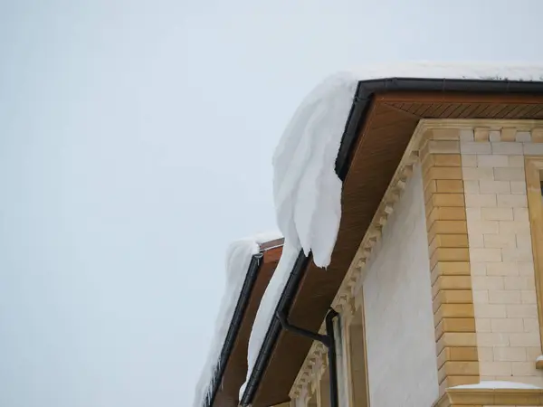 Schnee hängt vom Dach des Gebäudes. — Stockfoto